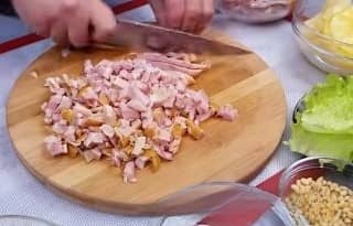 Шаг 2 Сначала у копчёных куриных окорочков отделяем мясо от косточек и нарезаем его мелким кубиком. Перекладываем нарезанное мясо в большую чашу, в которой будем смешивать салат.